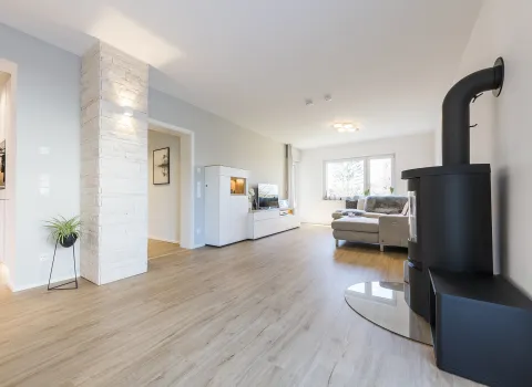 Helles, großes Wohnzimmer mit Kamin und Holzboden.