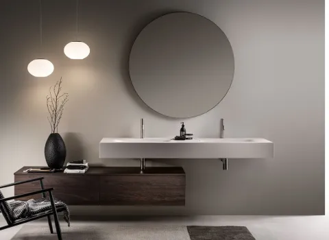 Eleganter Stocco Doppelwaschtisch mit durchgehender weißer Waschplatte, rundem Spiegel und dunklem Holzunterschrank.