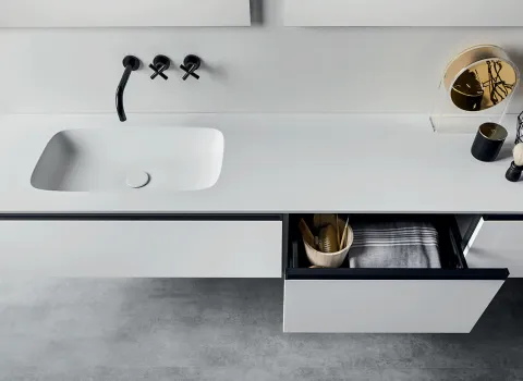 Minimalistisches Bad von Stocco mit weißem Waschtisch, schwarzen Wandarmaturen und geöffnetem Schubfach.