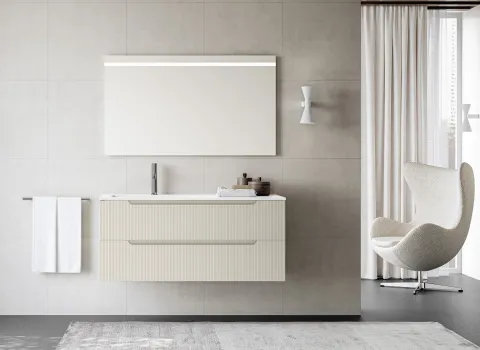Stocco Badmöbel mit geriffelter Front in Elfenbein und großem Spiegel vor Fliesenwand.