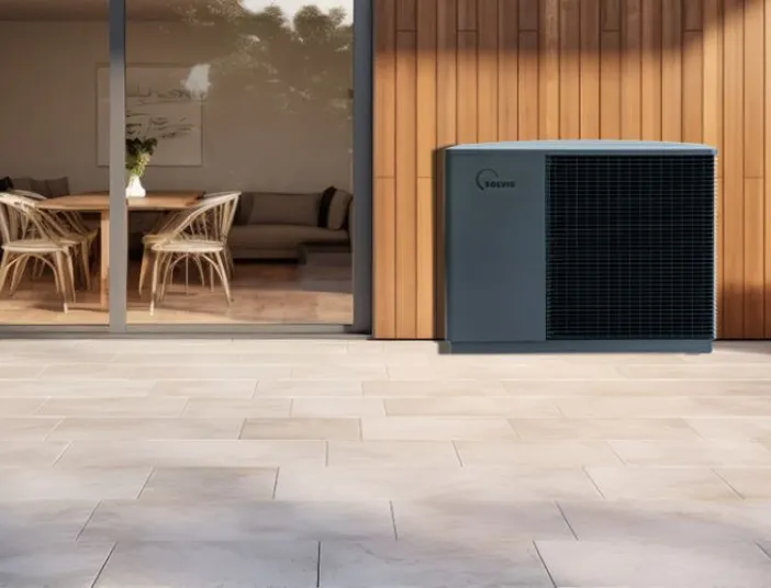 Eine Solvis-Wärmepumpe steht auf einer großzügigen Terrasse vor einer modernen Hausfassade mit Holz- und Glasflächen.